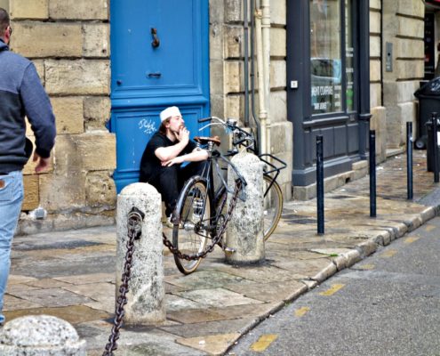 Homme assis devant une porte dans la rue