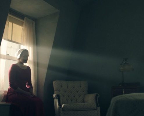 La servante écarlate assise en contre-jour devant la fenêtre de sa chambre