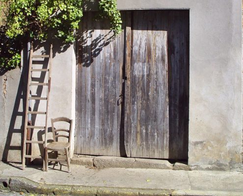 Vieille chaise vide en bois devant une vieille porte de grange