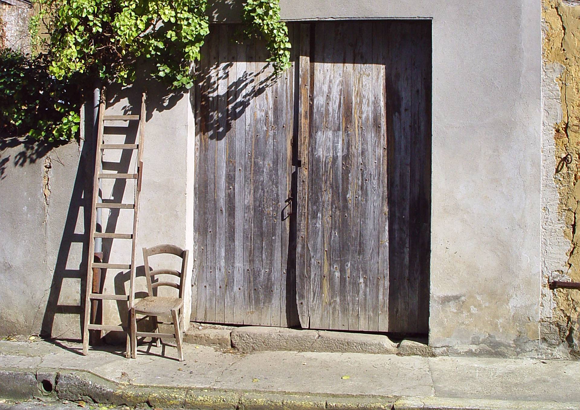 Vieille chaise vide en bois devant une vieille porte de grange